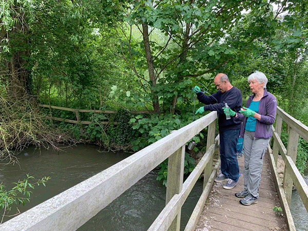 people sampling river on bridge