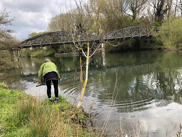 person using a pole to sample a river